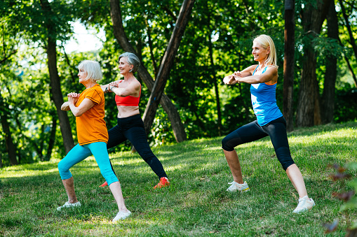 Group of beautiful sportive senior women training outdoors - Mature adults old friends doing fitness workout exercises in a park to stay healthy and fit
