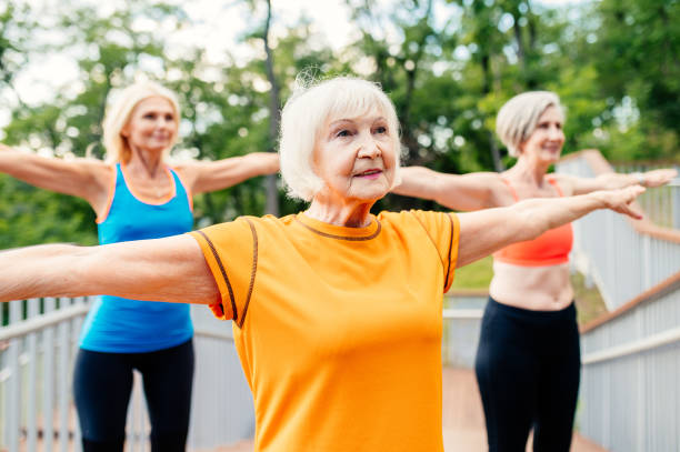 active senior women doing fitness in a park - fun senior adult aerobics exercise class imagens e fotografias de stock