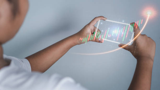 istock Hologram image of a candlestick chart from a phone on a person's hand. Offer trading concept, investment ideas 1437509449