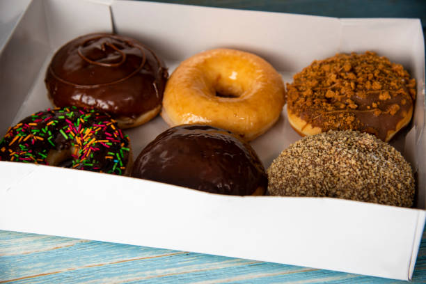 istock Doughnuts Box with Young Girl's Hand Taking One 1437510707