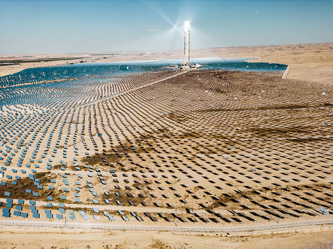 Collection solar thermal power station in the desert landscape. The mirrors focus sun rays onto the tower, producing steam in the process.  Negev desert near the kibbutz Ashalim, in Israel.