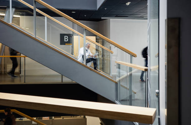 istock Teacher sitting on the staircase of a school building using digital tablet 1437515163