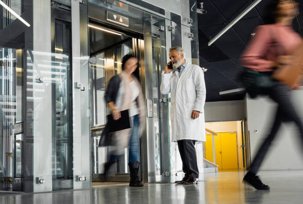 istock Doctor waiting for elevator talking on phone 1437515168
