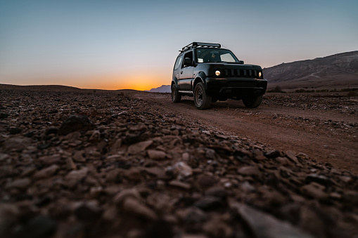 Small SUV 4x4 in Desert Landscape in Middle East. Surreal view of remote location during the day.