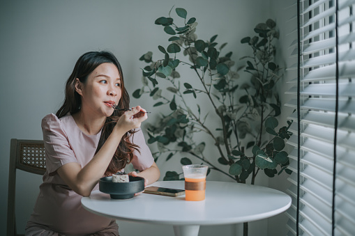 Asian Chinese Pregnant woman enjoying her dessert at cafe alone day dreaming