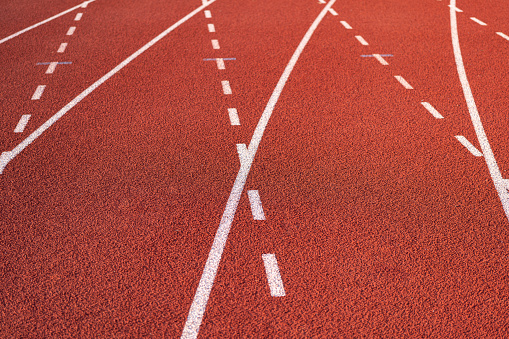 Running racktrack with traction rubber surface at the standard running court stadium, close-up. Sport equipment textured photo.