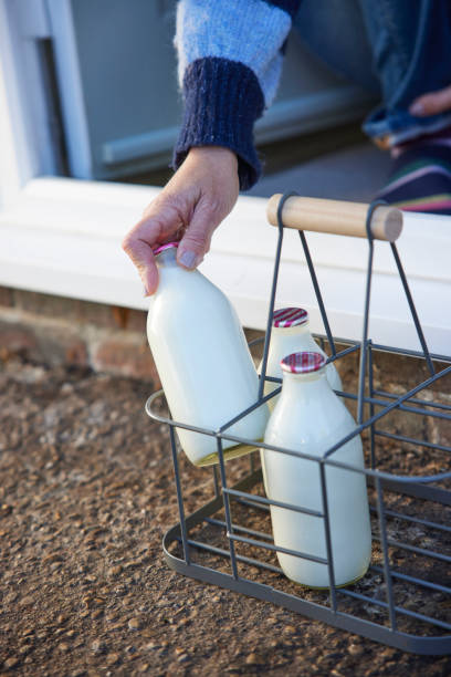 집 문 계단에서 우유 한 병을 줍는 사람 - milk bottle bottle milk doorstep 뉴스 사진 이미지