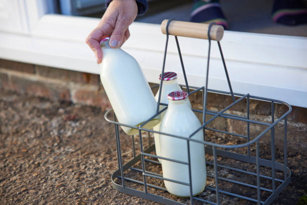 persona recogiendo la botella de leche del paso de la puerta de la casa - milkman fotografías e imágenes de stock