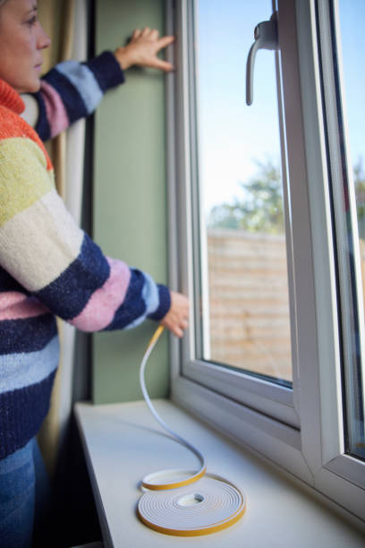 istock Woman Saving Enegy Insulating Home Putting Draught Excluder Tape On Window 1437519989