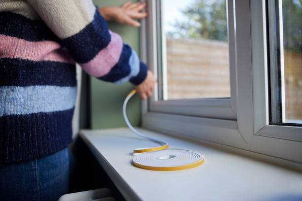 Woman Saving Enegy Insulating Home Putting Draught Excluder Tape On Window