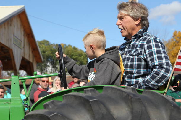 Father and son driving tractor in the parade The Sandwich Fair Held annually at Sandwich, NH, US on Columbus Day Weekends, October 8 - 10, 2022. The Grand Street Parade. sandwich new hampshire stock pictures, royalty-free photos & images