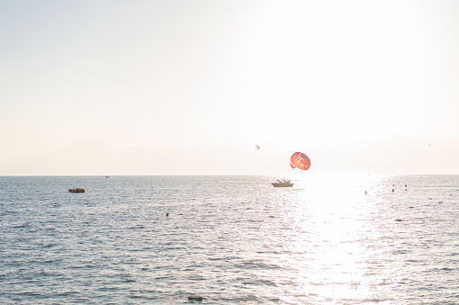 People parasailing in Antalya with a speedboat by sunset