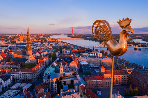 The golden rooster on a spire overlooking the old town of Riga in Latvia during sunset