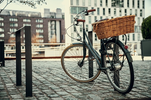 A close-up shot of a parked bicycle with a basket on a city street in the daytime