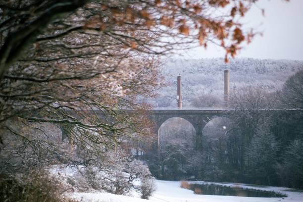 istock Bridge with arches and power plants in winter with tree branches in the foreground 1437527759