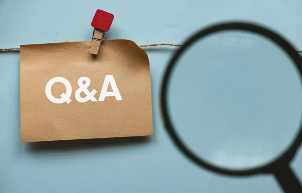 Brown paper hanging on the rope written with letter Q, A and ampersand with a blurry image of magnifying glass in front. Question and answer concept. stock photo