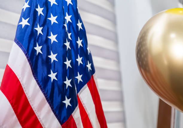 American flag on a white and grey colored curtains and with gold colored balloon