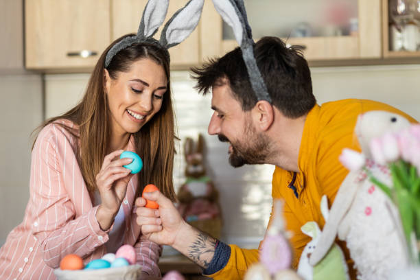 istock Newlywed couple with bunny ears and colored Easter eggs 1437534466