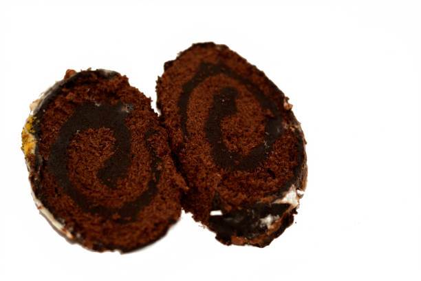 A chocolate cake roll Swiss roll, combination of light chocolate sponge cake with sweet vanilla whipped cream and chocolate ganache dessert, covered with white chocolate and pistachios A chocolate cake roll Swiss roll, combination of light chocolate sponge cake with sweet vanilla whipped cream and chocolate ganache dessert, covered with white chocolate and pistachios, selective focus brownie packaging stock pictures, royalty-free photos & images