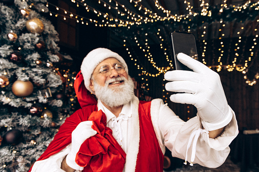 Happy, real, funny Santa Claus using phone