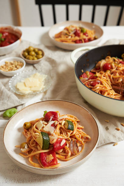 istock Vertical shot of pasta with vegetables and ingredients on a white table 1437539260