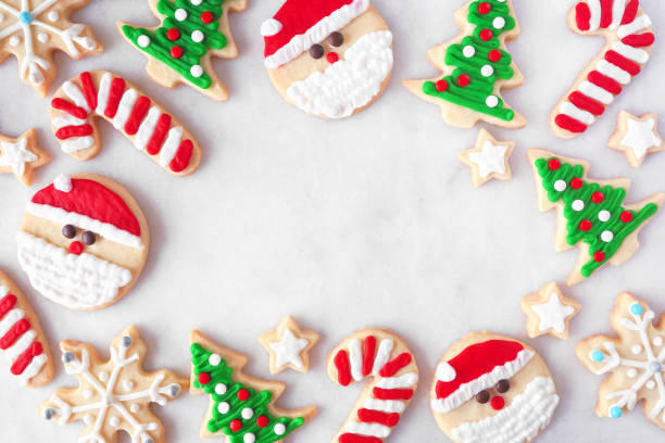 Cute Christmas cookie frame on a white marble background Cute Christmas cookie frame. Top down view on a white marble background with copy space. Holiday baking concept. Santa Claus, tree, snowflakes, candy canes, stars. white sugar cookie stock pictures, royalty-free photos & images