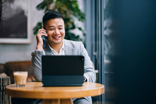 istock Smiling Businessman Talking On A Mobile Phone In The Cafe 1437543263