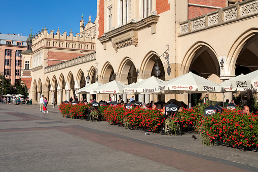 Cracow, Poland - September 1, 2022: Tourists sitting in restaurant and walking on Market Square in Cracow, Poland.
