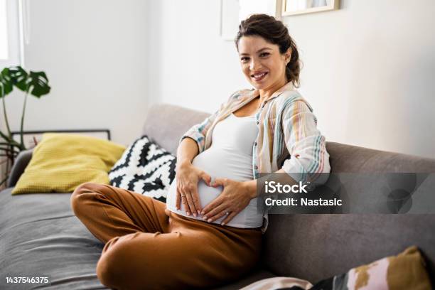 Smiling Pregnant Woman Holds Heart Shape With Hands On Pregnant Belly Stock Photo - Download Image Now