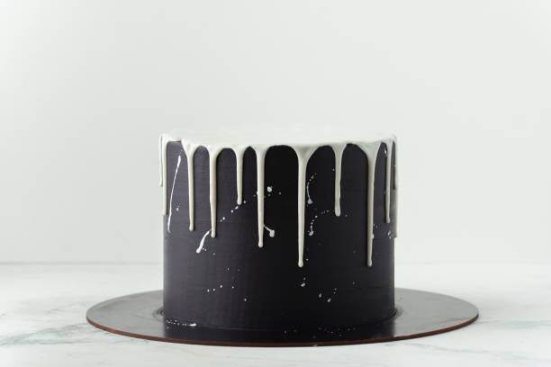 istock Black cake with white chocolate drips on the white background. Pouring chocolate on the cake. Chocolate drops on the cake 1437552652