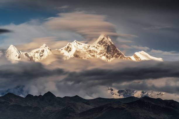 Massive snowy mountains covered by layers of clouds in Tibet