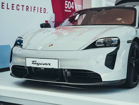 Vienna, Austria - June 28, 2022: Close up detail with the new Porsche Taycan electric sport car at a auto show in Vienna