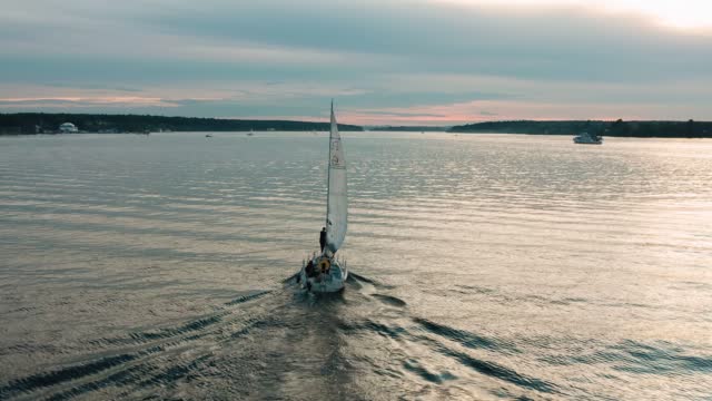 A pleasure yacht is sailing on the surface of the lake towards sunset. Very cool light