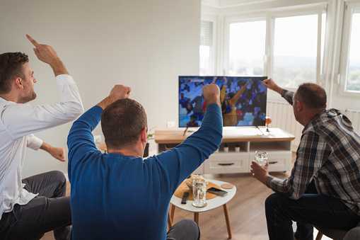 Football enthusiasts gathered at an apartment and celebrating their favorite team winning the game