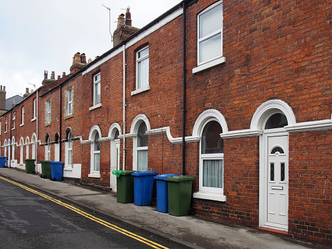 street of typical brick 19th century terraced houses in scarborough england with wheelie bins on the pavement