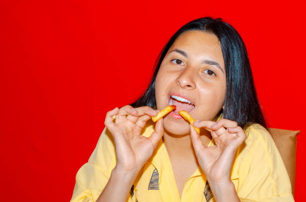 istock Woman eating fries with red background 1437567605