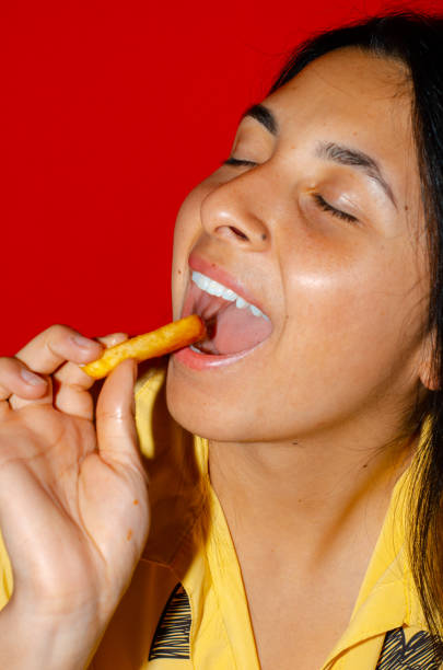 istock Woman eating fries with red background 1437567608