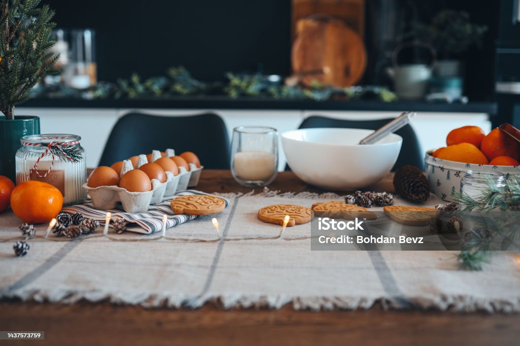 Ingredients for making Christmas cookies on the table against the backdrop of the kitchen. Plate with dough, milk, egg and New Year's decor Ingredients for making Christmas cookies on the table against the backdrop of the kitchen. Plate with dough, milk, egg and New Year's decor. Table Stock Photo