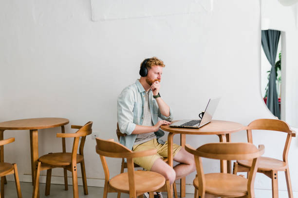 istock Ginger businessman using laptop and having video call at coffee shop 1437576941
