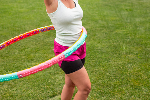 Woman exercising with a hula hoop on a meadow in summer