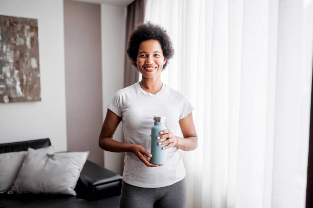 istock Sporty woman drinking water after intensive home workout 1437577588