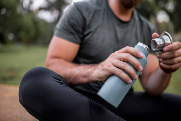 人間の手にある再利用可能なウォーターボトルの接写、喉の渇き、水分補給、使い捨てプラスチックの減少のコンセプト - water bottle 写真 ストックフォトと画像