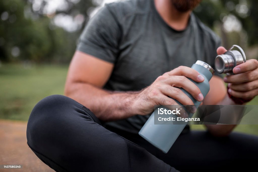 Close up of a reusable water bottle in a human hand, concept of thirst, rehydration and decreasing single use plastic Water Bottle Stock Photo