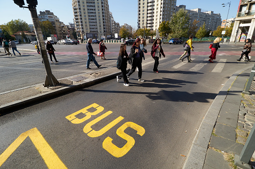 Bucharest, Romania - October 17, 2022: Pedestrians cross a street with a bus lane in United Nations Square in Bucharest, Romania. This image is for editorial use only.