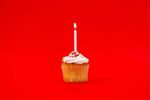 Cupcake with a candle on a red background