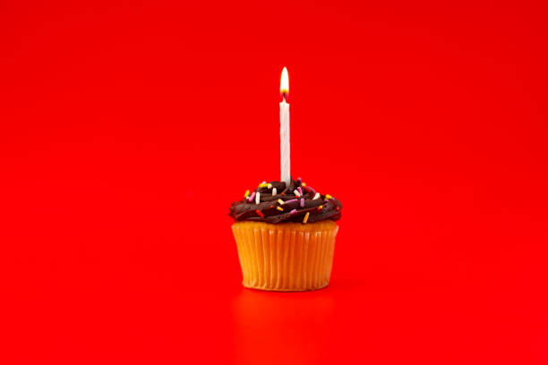 istock Cupcake with a candle on a red background 1437581169