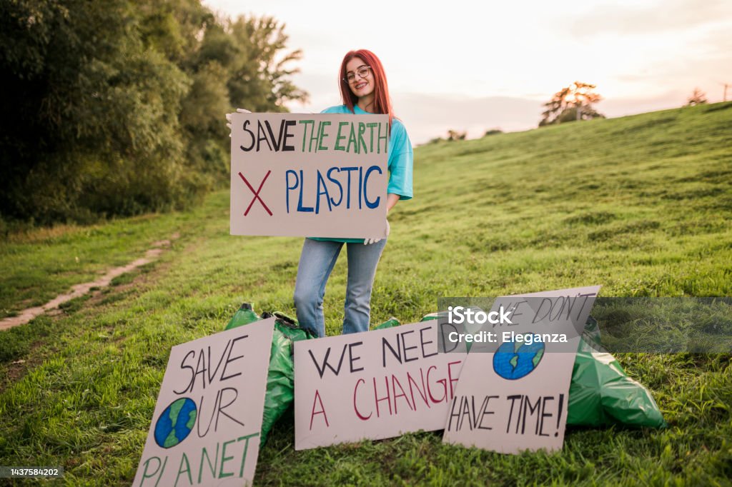Woman holding banner signs while going to a demonstration against climate change. Protest against global warming. Climate change protest concept. Adult Stock Photo