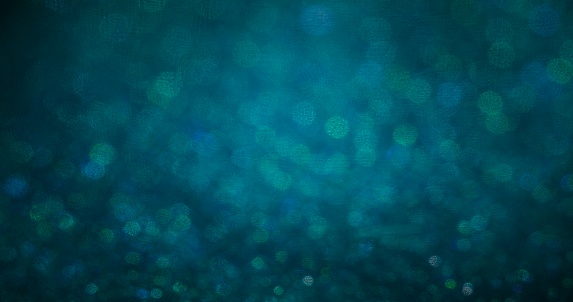 Defocused glow background. Bokeh circles texture. Shiny bubbles. Blur green blue particles glare on dark abstract overlay.