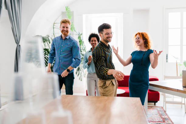 istock Business people having fun at the office, playing office games while on a break, tearing down a pyramid of plastic cups with a  ball 1437588353