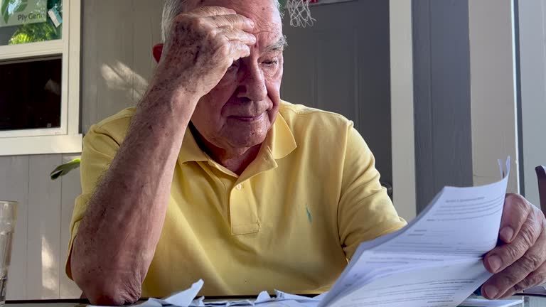 Stressed senior man looking at all his past due bills due the economical recession